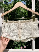 Short de crochet color crema, con cintura elástica y cordón ajustable con borlas.