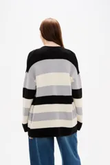 Saco de punto con diseño de rayas horizontales en negro, gris y blanco. Presenta cuello en V, cierre frontal con botones y bolsillos laterales.