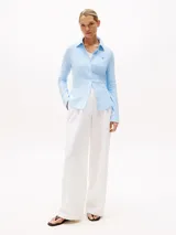 Camisa Tommy Hilfiger de corte slim, confeccionada en piqué de algodón elástico a rayas celestes y blancas, con cuello camisero, cierre de botones y logo bordado en el pecho.