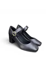 Zapato tipo Mary Jane de color blanco, con taco cuadrado medio y tira en el empeine con hebilla metálica dorada circular.