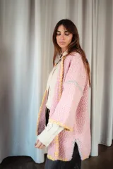 Saco oversize de tejido de punto en color rosa, con mangas caídas y detalles de bordado a mano en contraste en los bordes y costuras.