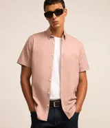 Camisa de manga corta color rosado, con cuello inglés, cierre frontal de botones y corte cómodo.