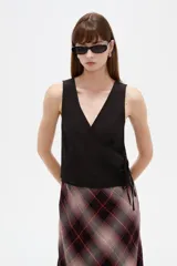 Musculosa de algodón sin mangas, de corte cruzado con cuello en V y diseño holgado, color blanco con estampado de lunares bordó y lazo lateral para ajustar.