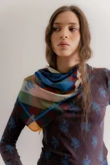 Remera de manga larga confeccionada en algodón elastizado, con cuello redondo y diseño ajustado al cuerpo. Presenta un estampado de rombos finos con motivos florales en tonos azules sobre una base de color marrón oscuro.