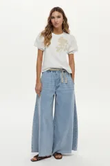 Jean wide leg color celeste, con cintura elástica ajustable mediante cordón y detalles de flecos en el ruedo.