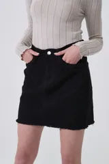 Falda mini de jean color negro, con diseño de cinco bolsillos y detalle de trenzado en los bolsillos delanteros. Presenta un ruedo deshilachado y cierre frontal con botón metálico.