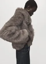Chaqueta corta de piel sintética con textura mullida, cuello solapa grande y mangas largas.