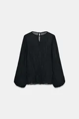 Blusa negra de manga larga abullonada, con tejido plisado y cuello redondo con abertura y botón en la espalda.
