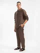 Chaqueta verde oliva de lino italiano, corte relajado, con tres bolsillos frontales y cierre con botones.