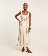 Vestido largo evasê sin mangas de color beige, con escote cuadrado y costuras verticales con bies en tono contrastante oscuro.