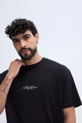 Remera oversize negra de manga corta, con calce amplio y estampa gráfica en la espalda con texto en tonos azules y dorados.
