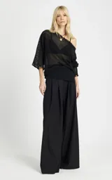 Blusa negra de punto calado con diseño amplio y transparente, escote de hombros descubiertos, mangas largas y puños acampanados.