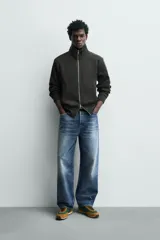 Chaqueta regular fit confeccionada en tejido interlock de algodón con elasticidad. Presenta cuello subido, manga larga, bolsillos de vivo en la cadera, acabados en rib y cierre frontal con cremallera.