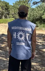 Remera sin mangas de algodón con lavado acid wash, color azul. Estampado grande en la espalda con el texto "MEDITERRANEAN HOT SEASON", donde la letra 'O' de 'HOT' es reemplazada por un sol estilizado.