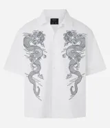 Camisa de manga corta, cuello inglés, abotonada, de corte boxy. Confeccionada en sarga de algodón, presenta un estampado simétrico de dragones en color gris oscuro en el frente.