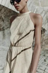 Vestido midi de cuello halter con diseño de cuadros, cintura elástica y abertura en la espalda. Cuenta con cierre de cremallera oculta y botón en la parte posterior.