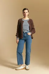 Cardigan de punto color terracota con diseño de trenzas verticales, cuello redondo y cierre frontal con botones metálicos. Presenta mangas largas con puños ajustados y un calce holgado.