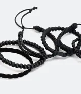 Set de seis pulseras de estilo casual, todas en color negro. Incluye tres pulseras trenzadas ajustables con cordón y tres pulseras con cuentas elásticas (algunas de cuentas lisas y otras de cuentas texturizadas).