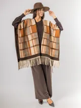 Ruana abierta con diseño de cuadros en tonos azul, beige y blanco, con terminación de flecos en el ruedo.