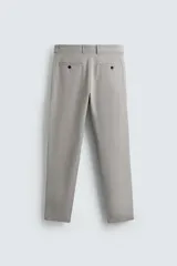 Pantalón chino de corte slim fit, confeccionado en tejido elástico. Presenta bolsillos frontales, bolsillos traseros de vivo con botón y cierre frontal con cremallera y botón.