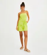 Vestido corto sin breteles color verde lima, confeccionado en lino y algodón. Presenta bolsillos laterales y bordado frontal de una palmera y conchas marinas.