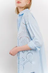 Camisa celeste de algodón liviano con bordado calado tipo broderie, manga larga con puño angosto y botones al frente.