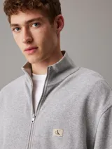 Sweater Calvin Klein gris de algodón regenerativo con textura gofrada, cuello alto, cierre de cremallera metálico, puños y bajo de canalé, y logo bordado en el pecho.