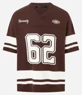 Remera oversized deportiva color marrón con cuello en V, rayas blancas en las mangas y en la parte inferior, y el número "62" estampado en blanco en el frente. Incluye el bordado "Humanity" y un logo de globo terráqueo.