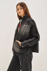 Campera acolchada de corte holgado con diseño de costuras cuadradas, cierre frontal con cremallera y cuello alto. Presenta un acabado lavado en tonos gris y negro.