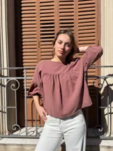 Blusa color chocolate de diseño holgado, con cuello redondo, frunce frontal y mangas abullonadas con puños ajustados.