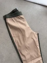 Pantalón de cuero sintético beige con paneles laterales y pretina elástica en color verde militar.