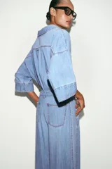 Jeans de tiro medio con corte wide leg y pinzas delanteras. Presenta bolsillos frontales, bolsillos de plastrón en la parte trasera, cierre frontal con cremallera, botón interior y ganchos metálicos.