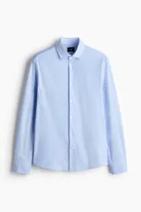 Camisa H&M de corte slim fit en mezcla de algodón con rayas finas celestes y blancas. Presenta cuello italiano, cierre frontal con botones y mangas largas.