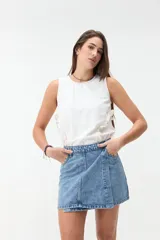 Minifalda de denim celeste con diseño cruzado, bolsillos frontales y costuras pespuntadas visibles.