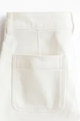 Short de denim de algodón levemente elástico, modelo de tiro alto con cierre y botón, bolsillos delanteros de parche con ribete y bolsillos traseros abiertos.