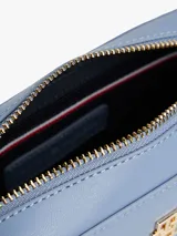 Bandolera Tommy Hilfiger azul con correa ajustable negra, cierre superior y logo dorado de la marca en el frente.