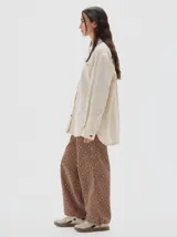 Camisa oversized de jean color crema, con botones rojos en forma de fresa y pespuntes a contratono. Tiene el logo "PASTICHE" bordado en rojo en el pecho.