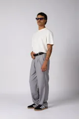 Pantalón sastrero de corte baggy, color beige, con pinzas frontales, cierre de botón y cremallera, y bolsillos laterales.