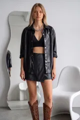 Short pollera negro de efecto cuero, con diseño cruzado en el frente y cintura alta.
