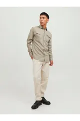 Camisa de denim color beige, con cuello clásico, cierre con botones y dos bolsillos frontales con solapa abotonada. Corte slim.