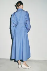 Vestido midi de corte camisero con estampado de rayas verticales, cuello solapa, manga larga con puños y cierre frontal con botones. Incluye un cinturón de lazada en el mismo tejido y bolsillos laterales ocultos.
