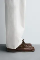 Mocasín náutico de cuero marrón, con cordones de cuero, ojales metálicos y detalles en gamuza a tono.