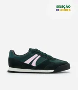Championes estilo vintage de inspiración deportiva, color verde oscuro con detalles en rosa claro. Presentan puntera redonda, cierre mediante cordones y suela plana con base blanca y borde negro.