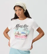 Remera de algodón blanca, de manga corta y cuello redondo, con estampa frontal inspirada en paisajes tropicales y detalles de lentejuelas.