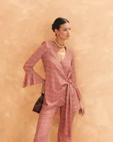 Pantalón acampanado de talle alto con cinturilla de goma en la parte trasera y cremallera lateral, con estampado geométrico en tonos naranja y azul.