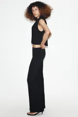Chaleco corto de Zara con cuello solapa, diseño sin mangas con hombreras y forro interior. Presenta un corte estructurado con cierre frontal mediante botón oculto.