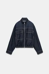 Cazadora bomber de denim oscuro con cuello subido, manga larga y bolsillos frontales con solapa. Presenta cierre frontal de cremallera y bajo elástico.