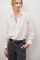 Camisa blanca de manga larga con cuello clásico y cierre de botones. Presenta un patrón de rayas verticales sutiles y transparentes.
