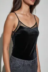 Body de terciopelo negro con escote recto y detalle de encaje transparente en la parte superior. Presenta breteles finos ajustables.