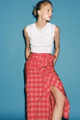 Falda midi de tiro medio, con estampado a cuadros vichy en tonos rojo y rosado, detalle de volantes en el delantero y cierre lateral con cremallera oculta.